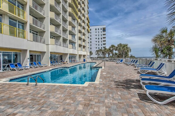 A pool area with blue lounge chairs and a brick floor. - 2 Mi to Barefoot Landing: Beachfront Resort Studio (North Myrtle Beach)