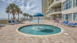 A pool area with lounge chairs and a palm tree.