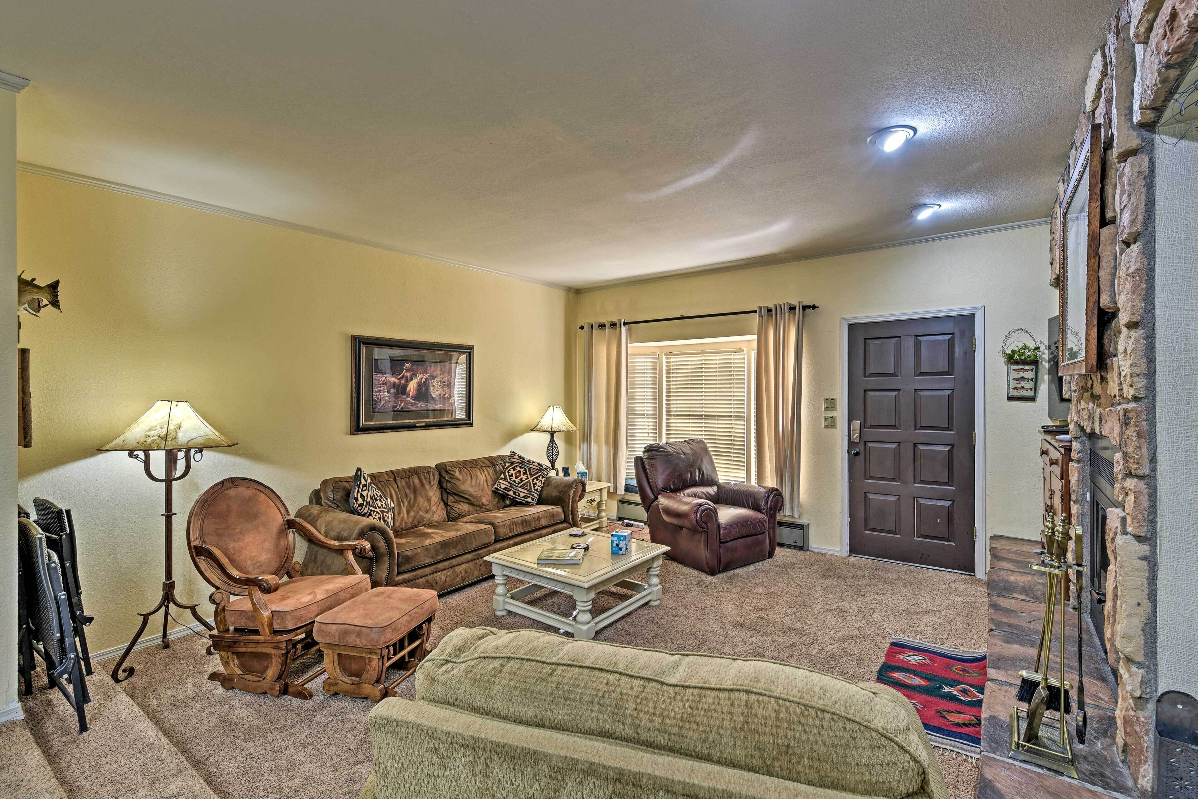 A living room with a brown leather sofa, a wooden coffee table, a green armchair, and a fireplace.