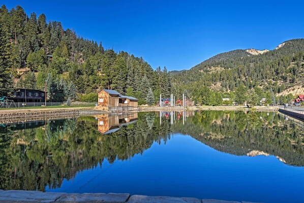A cabin by a calm lake with a forested mountain backdrop. - Red River Townhome With Balcony & Mtn Views! (Red River)