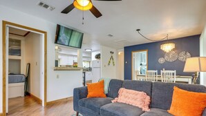 A living room with a grey sofa, orange pillows, a ceiling fan, and a dining area with a table and chairs. - Canyon Lake Home w/ Resort Amenities & Fire Pit! (Canyon Lake)
