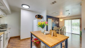 A modern kitchen with white cabinets, a wooden dining table, and a vase with flowers. - Canyon Lake Home w/ Resort Amenities & Fire Pit! (Canyon Lake)