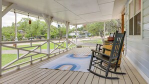 A covered porch with a wooden floor, a rocking chair, and a view of the surrounding greenery and houses. - Canyon Lake Home w/ Resort Amenities & Fire Pit! (Canyon Lake)