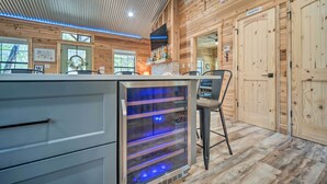 A modern kitchen with a built-in wine cooler, wooden walls, and a visible pantry. - 'lakewood Secret' Cabin ~ 4 Mi to The Lake! (Canyon Lake)
