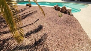 A pool area with a covered patio, palm trees, and a building with a tiled roof. - NEW! FAMILY FUN, ALOHA, Tropical Jericho with POOL (Lake Havasu City)