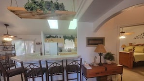 A kitchen with a central island, bar stools, a wooden table, and a lamp. - NEW! FAMILY FUN, ALOHA, Tropical Jericho with POOL (Lake Havasu City)