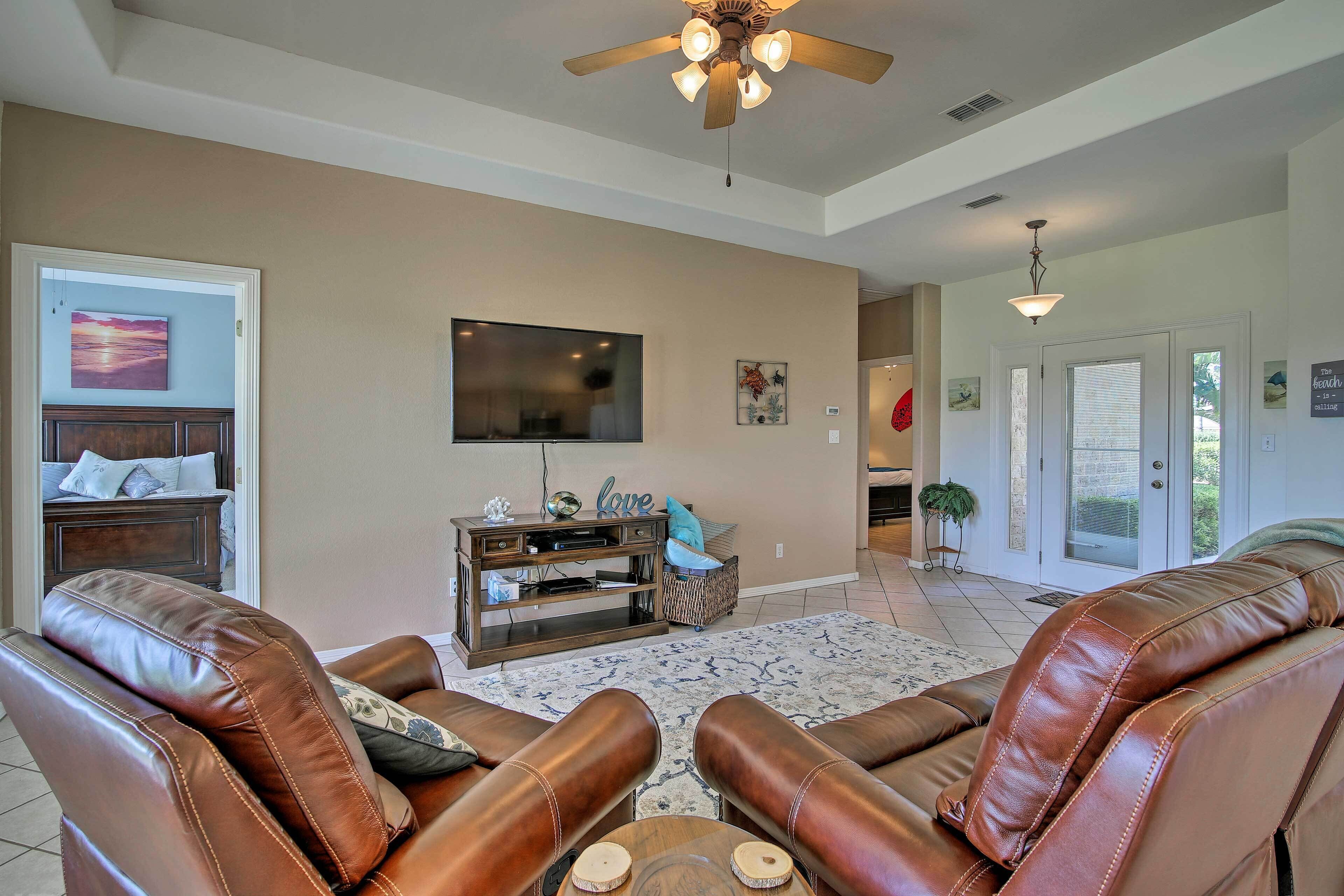 A living room with leather recliner chairs, a wooden entertainment center, and a ceiling fan.