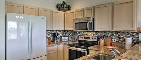 A kitchen with a stainless steel refrigerator, microwave, stove, and sink.
