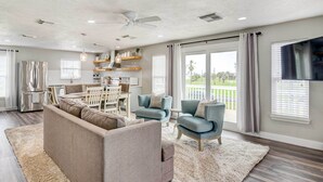 Un salon moderne comprenant un canapé, des fauteuils, un coin repas et une cuisine.