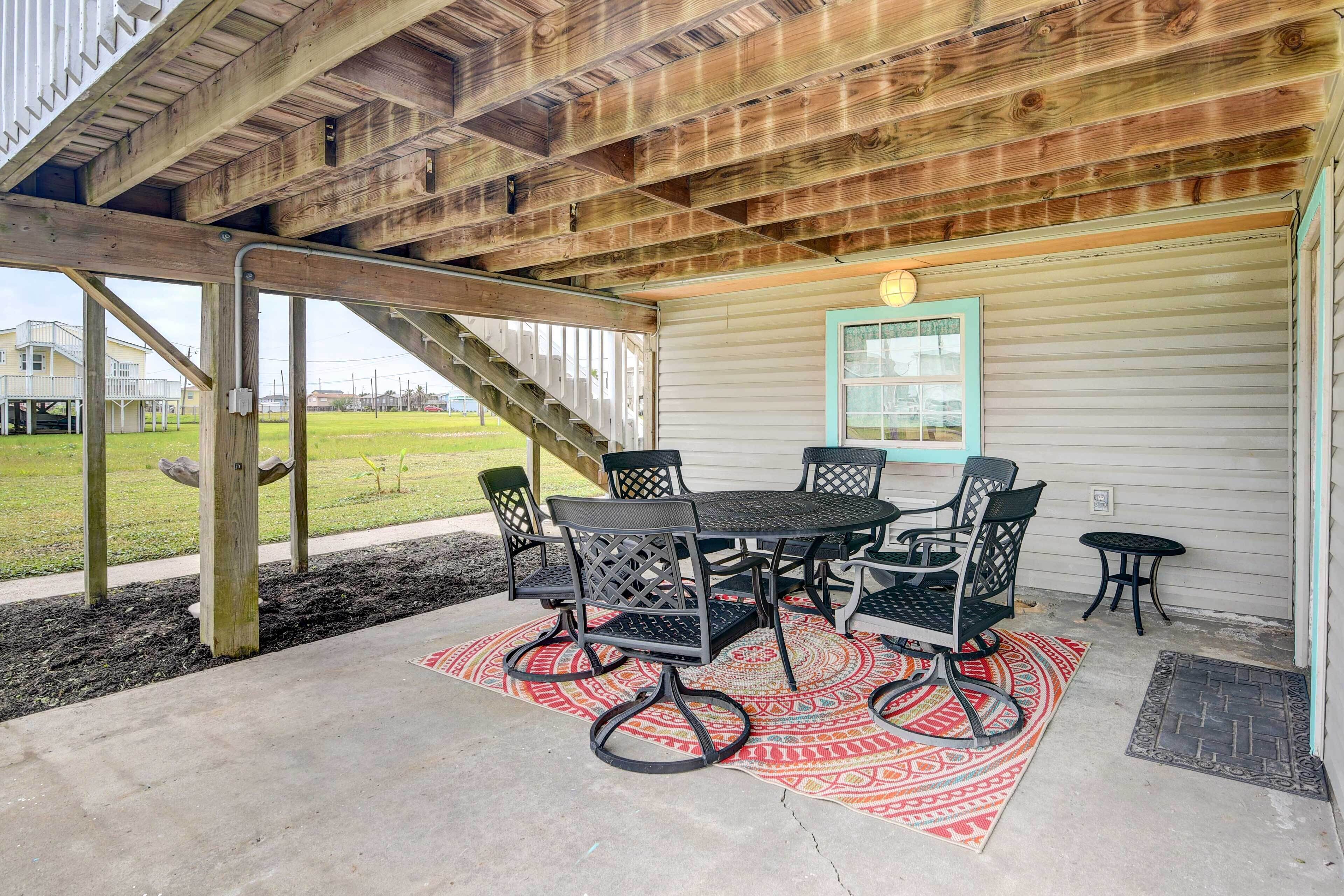 Un patio techado con mesa y sillas, techo de madera y vista a un área con césped.