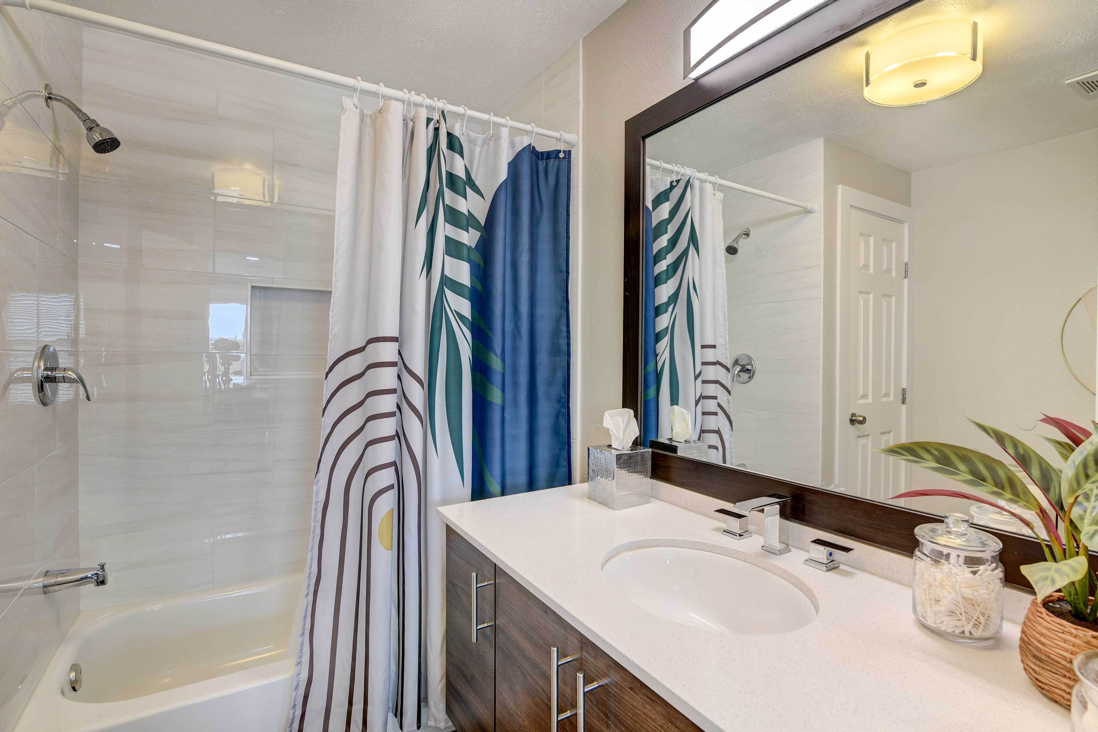 A modern bathroom with a bathtub, a shower, a vanity with two sinks, and a large mirror.