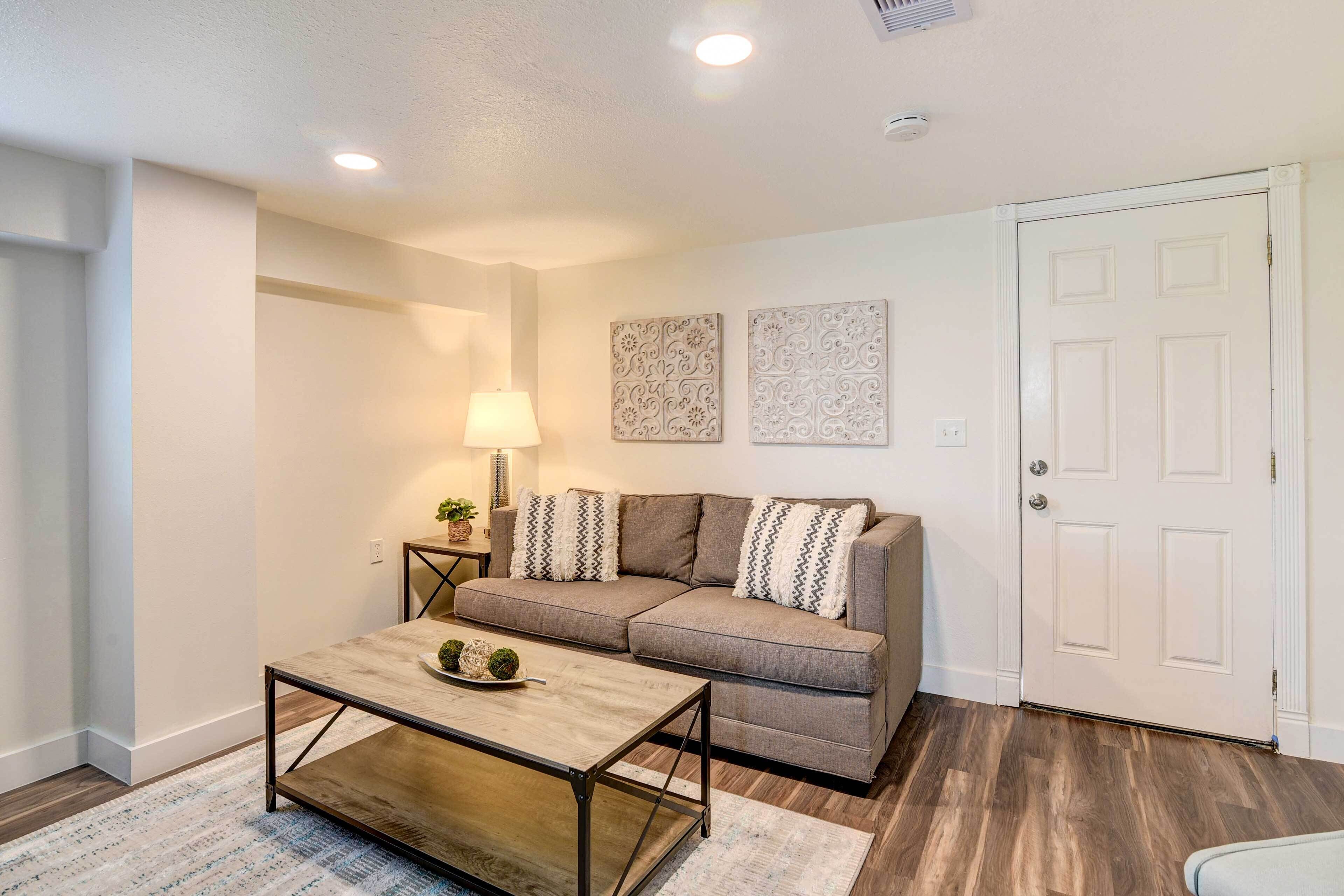 A living room with a sofa, coffee table, lamp, and decorative wall pieces.