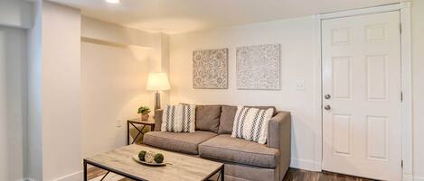 A living room with a sofa, coffee table, lamp, and decorative wall pieces.