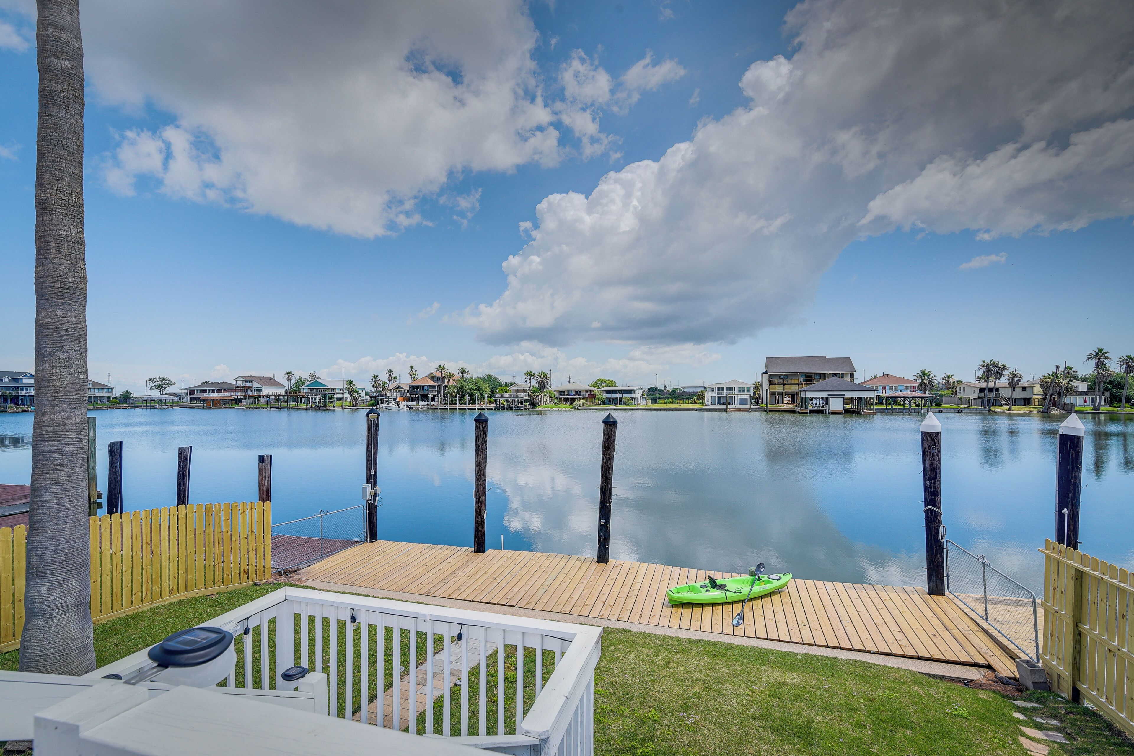 Une terrasse au bord de l’eau avec un kayak, une terrasse en bois et une vue sur l’eau et les bâtiments environnants.