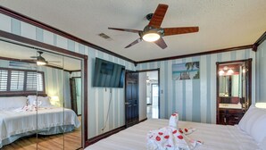 A hotel room with a large bed, a ceiling fan, a TV, and a mirror. - Waterfront Galveston Bay Retreat - 4 Mi to Beach! (Galveston)