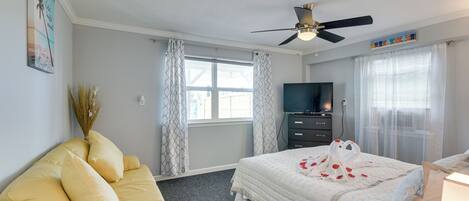 Une chambre à coucher avec un lit, un canapé, un ventilateur de plafond et un téléviseur.