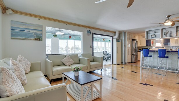 A spacious living area with a sofa, coffee table, and a kitchen area with a bar. - Waterfront Galveston Bay Retreat - 4 Mi to Beach! (Galveston)