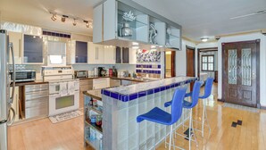 A modern kitchen with a central island, bar stools, and a dining area. - Waterfront Galveston Bay Retreat - 4 Mi to Beach! (Galveston)