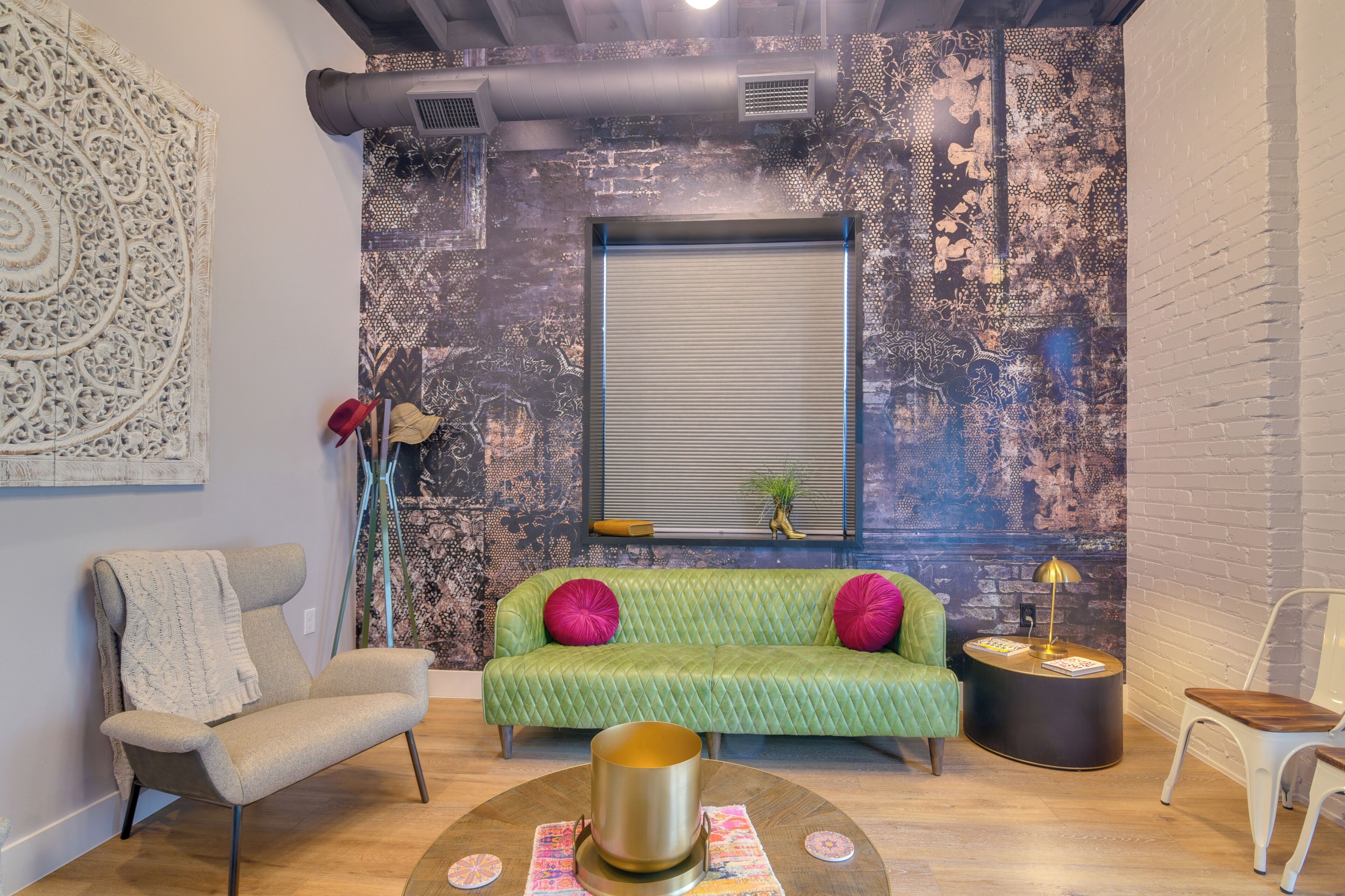 A cozy living room with a green sofa, a beige armchair, and a round coffee table.