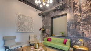 Un salon moderne avec un canapé vert, deux fauteuils, une table basse ronde et un élément décoratif mural.