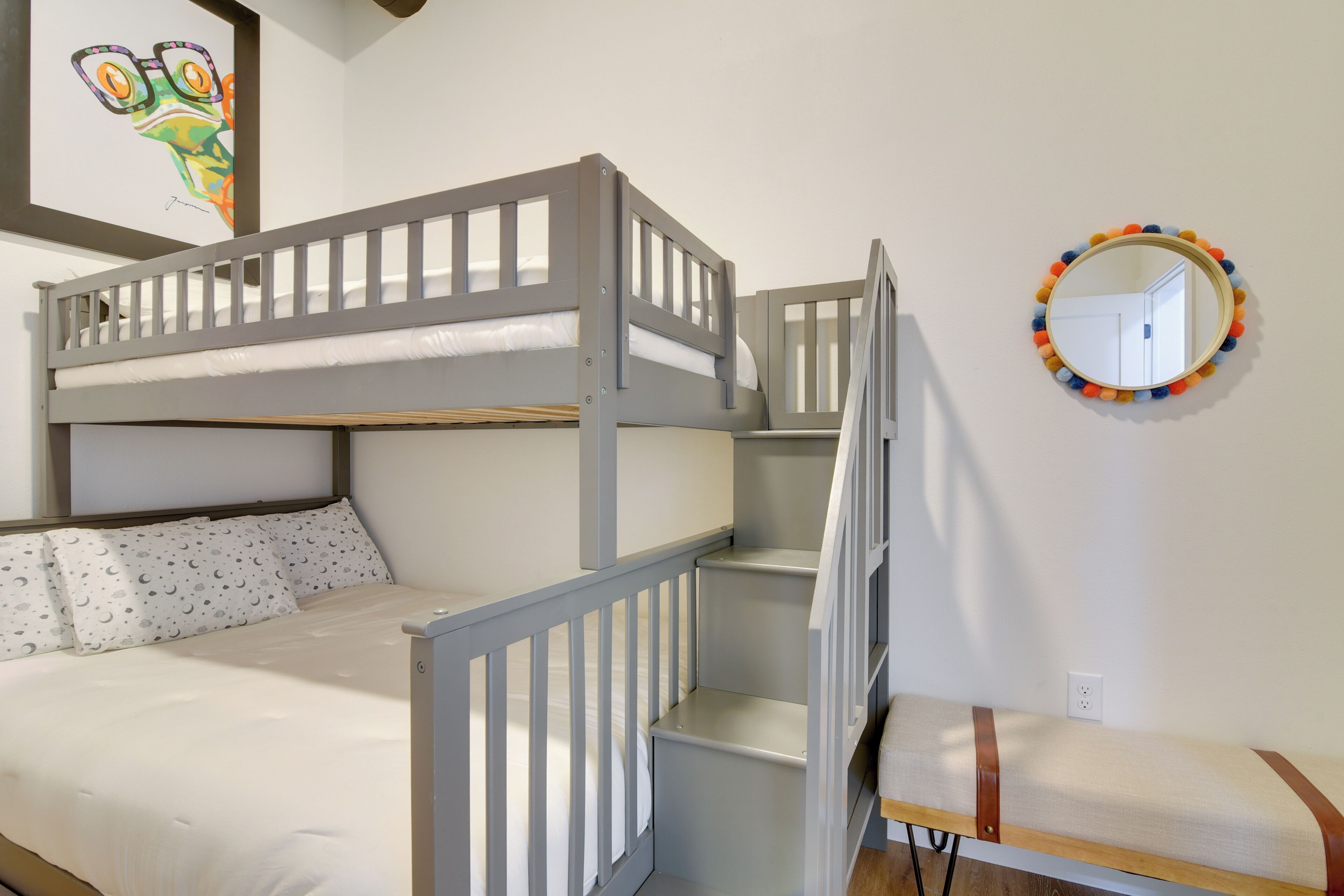 Een stapelbed met een witte matras en een onderste bed met een kussen met dessin.