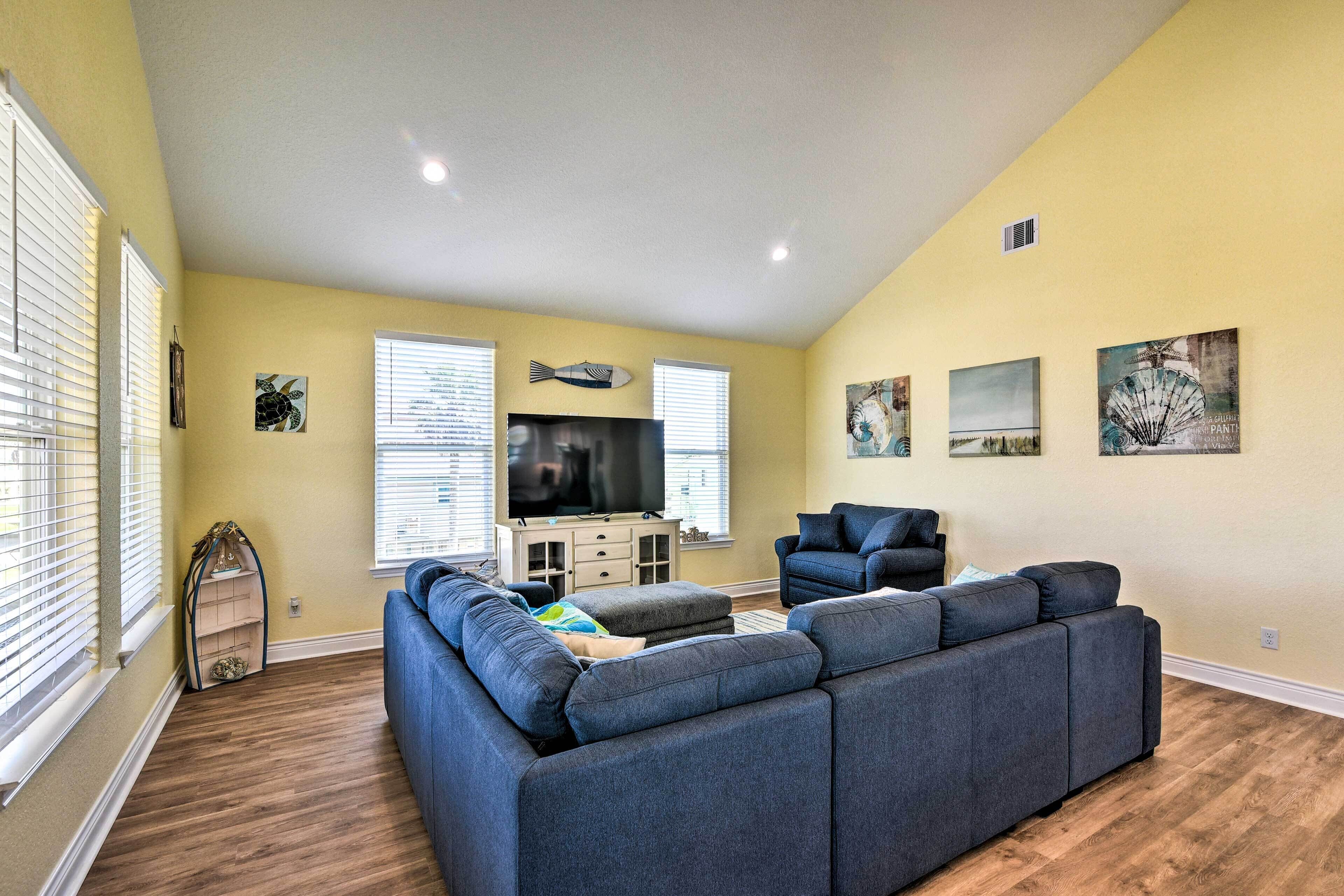 A living room with a sectional sofa, a television, and artwork on the walls.