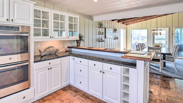 A kitchen with white cabinetry, a granite countertop, and a fish sculpture. There is a dining area with a table and chairs visible through an open door.