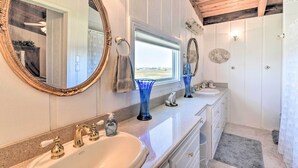 A bathroom with two sinks, a large mirror, and a shower area.