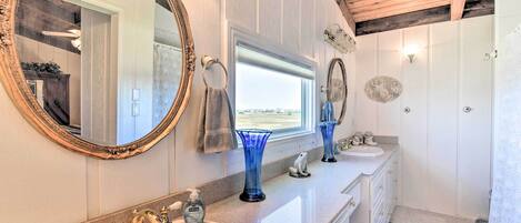 A bathroom with two sinks, a large mirror, and a window.