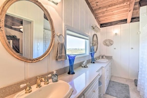 Une salle de bain avec deux lavabos, un grand miroir et un espace douche.