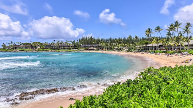 A beachfront resort with a sandy beach, clear turquoise waters, and lush greenery. - Bright & Airy Lahaina Condo - Walk to Beach! (Kapalua)