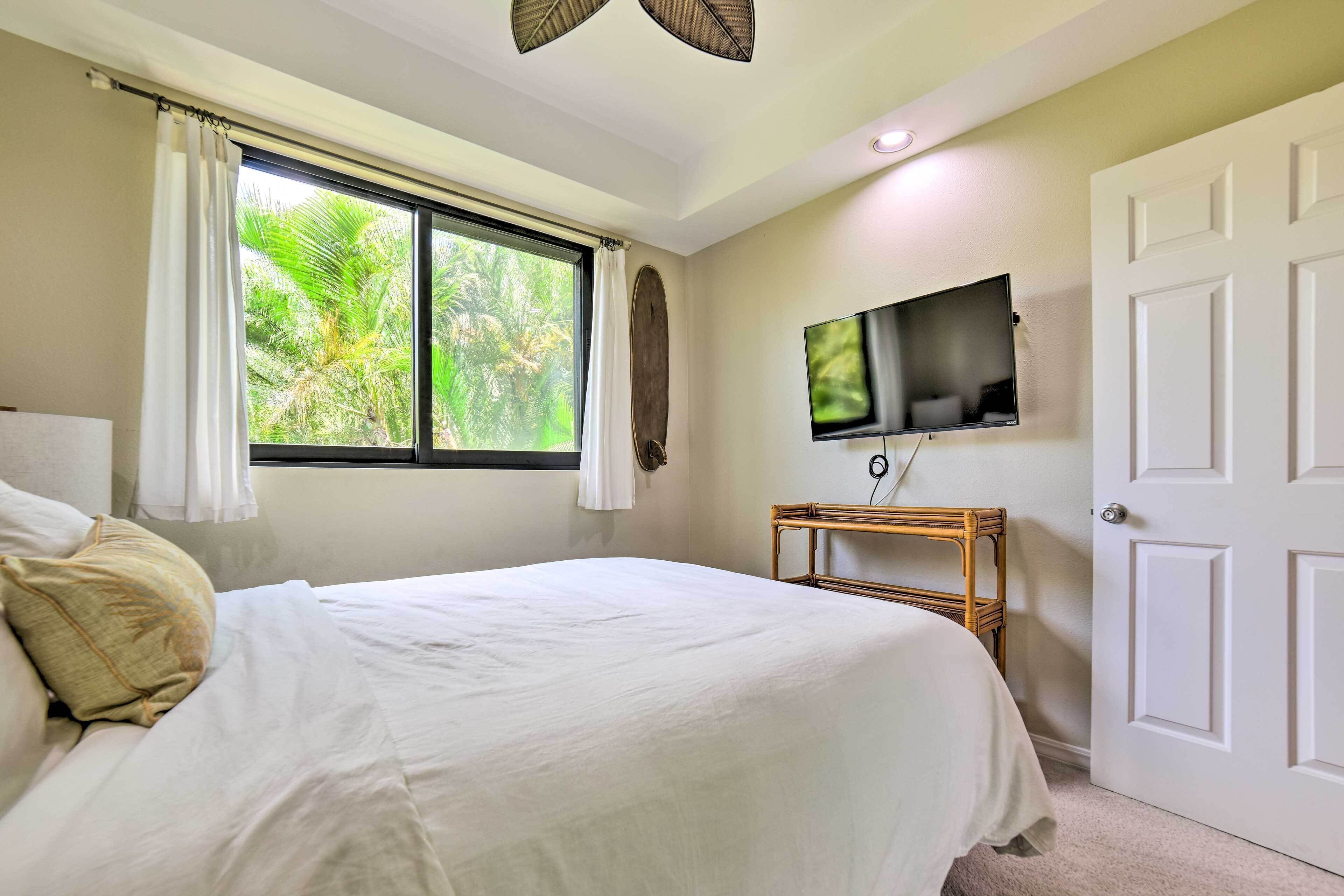 Quarto com cama, televisão, janela com cortinas e porta.
