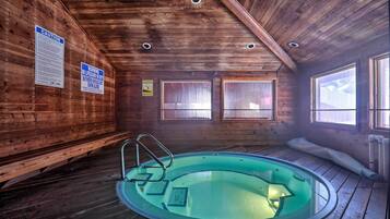 Una cabaña de madera con piscina, paredes de madera y techo con iluminación empotrada.
