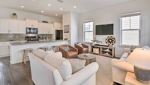 A modern living room with a white sofa, a coffee table, and a TV mounted on the wall. - Upscale Santa Rosa Beach Vacation Rental! (Santa Rosa Beach)
