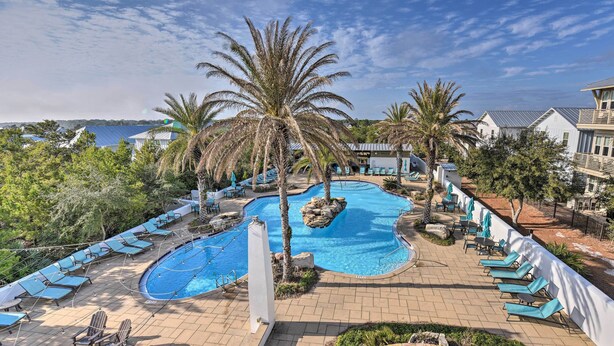 A pool area with lounge chairs, palm trees, and a view of the ocean. - Upscale Santa Rosa Beach Vacation Rental! (Santa Rosa Beach)