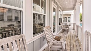 A covered porch with wooden chairs and a table, large windows, and a view of a house. - Upscale Santa Rosa Beach Vacation Rental! (Santa Rosa Beach)