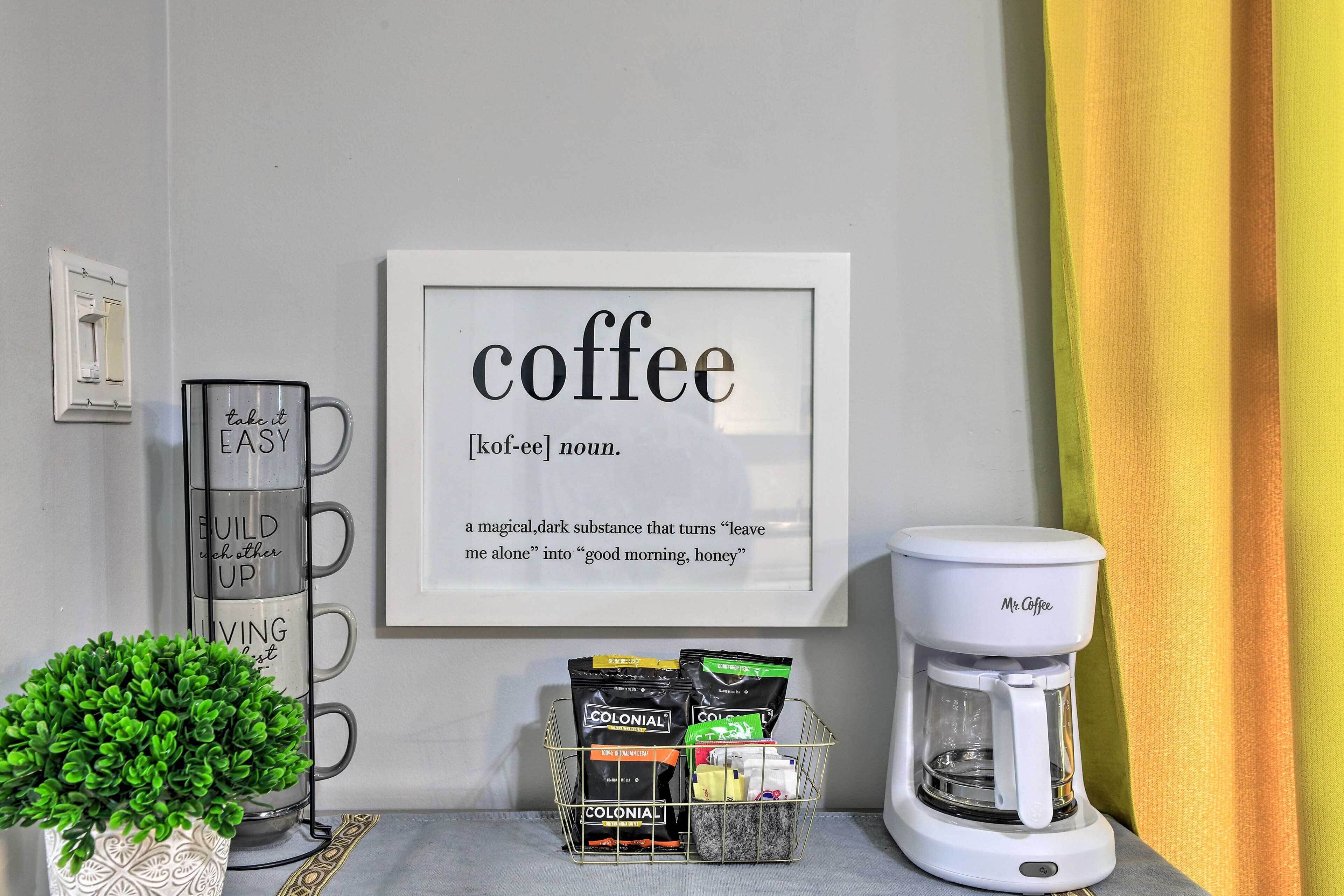 A coffee station with a framed quote, a coffee maker, and a basket of coffee pods.