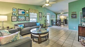 A living room with a grey sofa, a glass coffee table, and a ceiling fan. - North Port Escape w/ Pool ~ 12 Mi to Beach! (North Port)