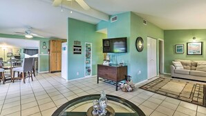 A living room with a dining area, a TV mounted on the wall, and a ceiling fan. - North Port Escape w/ Pool ~ 12 Mi to Beach! (North Port)