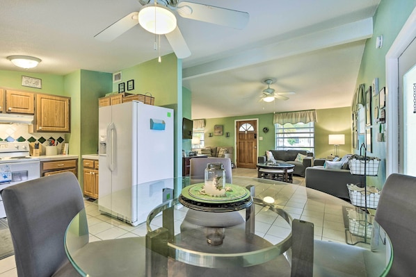 A modern kitchen with wooden cabinets, a white refrigerator, and a dining area with a glass table and chairs.