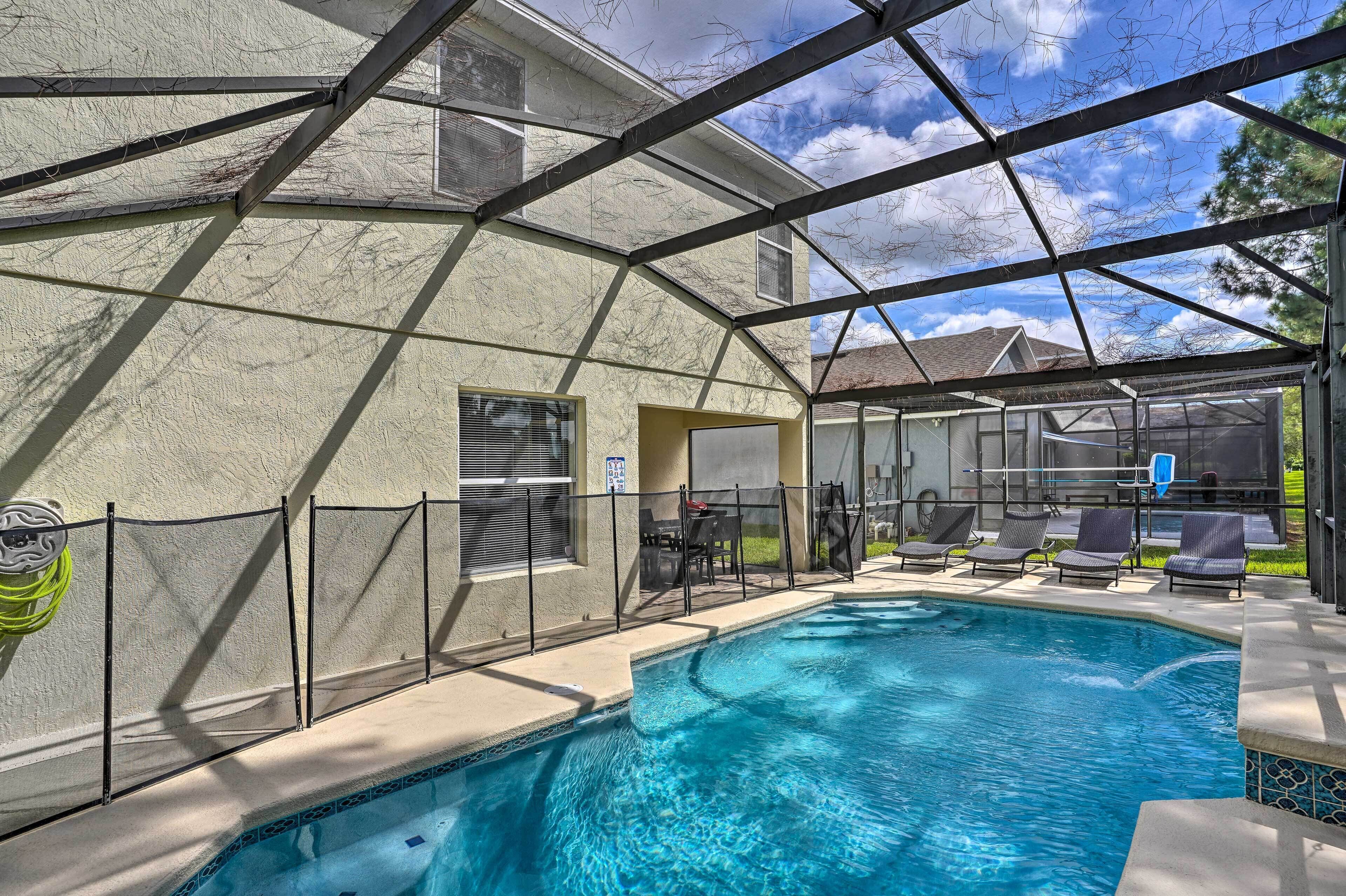 A covered swimming pool with a view of a house and a clear sky.