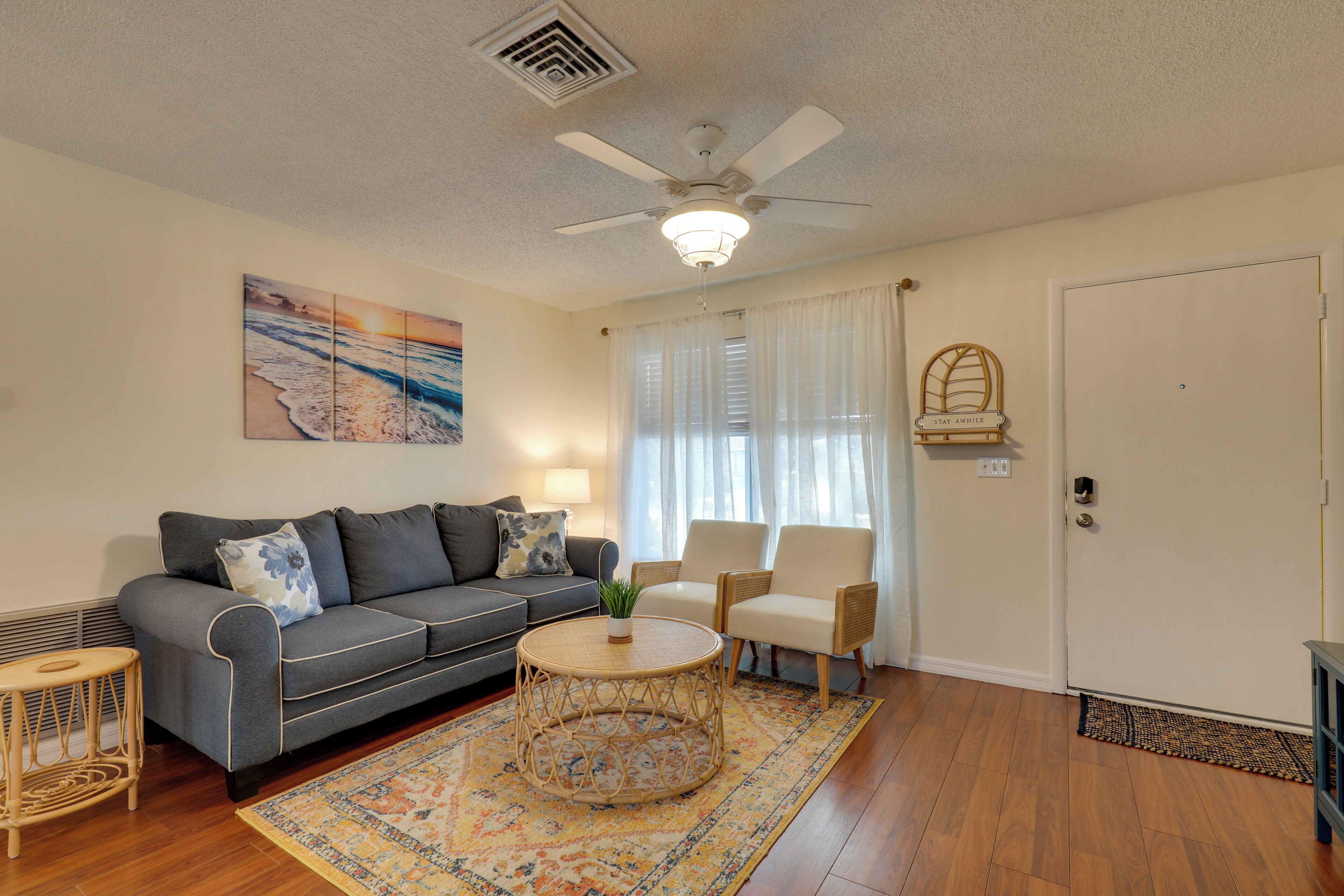 A living room with a gray sofa, two armchairs, a coffee table, and a ceiling fan.