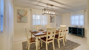 A dining area with a wooden table, white chairs, and a blue cabinet.