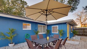 A patio with a table and chairs, a large umbrella, and potted plants.