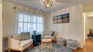 A living room with a sofa, armchair, round table, and ottomans.