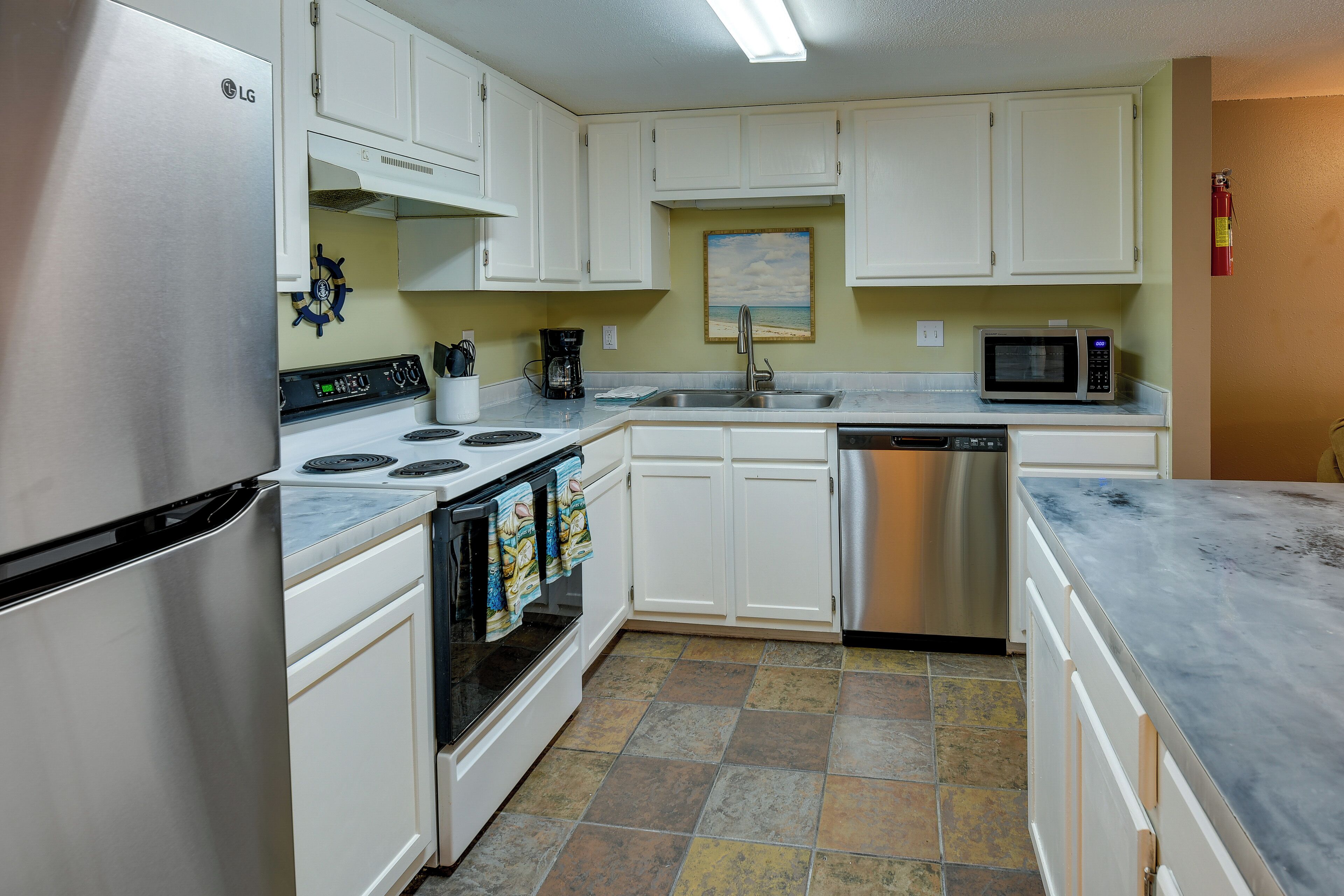 A kitchen with white cabinets, a stove, a microwave, and a dishwasher.