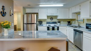 A kitchen with white cabinets, a stainless steel refrigerator, a stove, and a dishwasher. - Breezy Fort Walton Townhome ~ 5 Mi to Beach! (Fort Walton Beach)