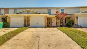 A row of townhouses with attached garages, a small front yard, and a clear sky. - Breezy Fort Walton Townhome ~ 5 Mi to Beach! (Fort Walton Beach)