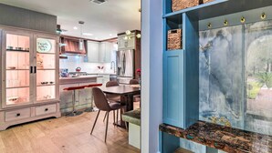 A modern kitchen with wooden cabinets, a dining area with a bench, and a view of the outdoors through a glass door. - Emerald Coast Vacation Rental: 1 Mi to Beach (Shalimar)