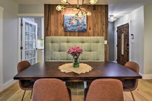 Un comedor con una mesa de madera, un banco acolchado y un jarrón de flores.